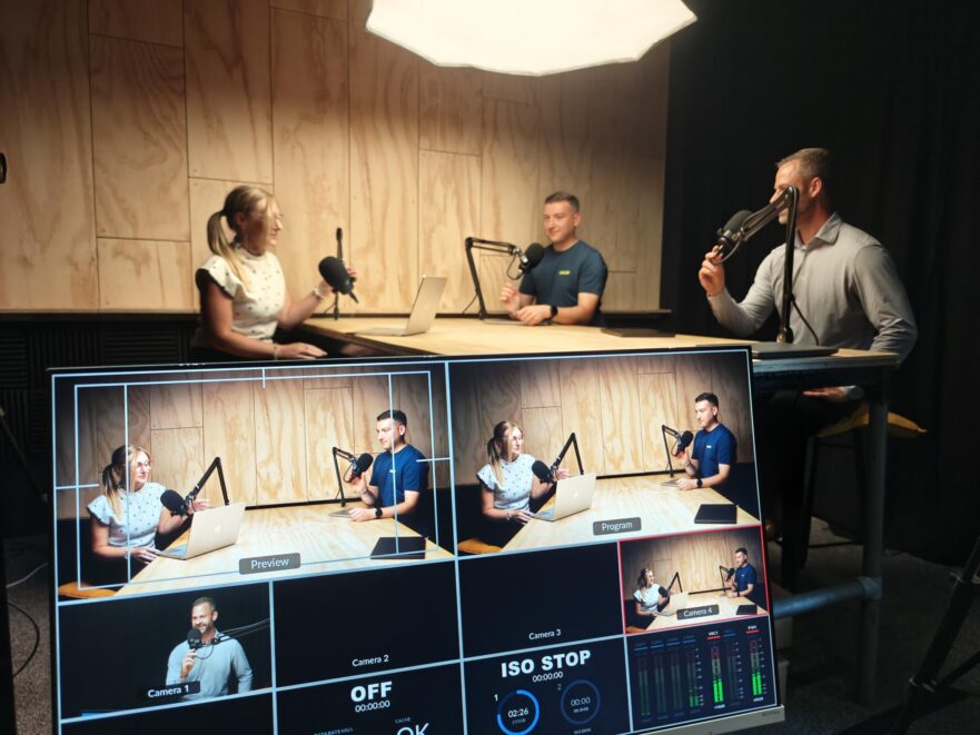 Three people sat at a table in a podcast studio