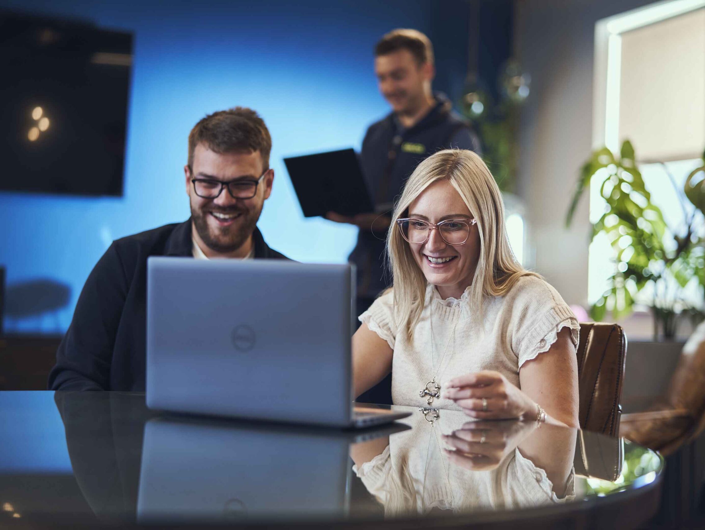 Three people working at a table smiling